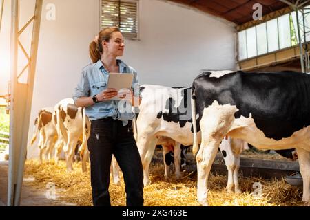 Eine Viehzüchterin, die Viehzucht inspiziert. Landarbeiterin A mit digitalem Tablet in einem Milchbetrieb. Stockfoto