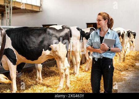 Viehzüchterin, die Viehzucht kontrolliert. Landarbeiterin A mit digitalem Tablet in einem Milchbetrieb. Stockfoto