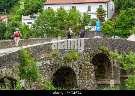 Pilger auf dem Jakobsweg über die mittelalterliche Brücke über den Fluss Arga, die sich Trinidad de Arga nähert Stockfoto