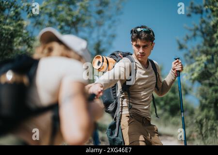 Junge Paare wandern und helfen sich gegenseitig auf einem Weg in einem Wald Stockfoto