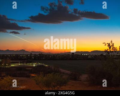 Ein glühender Sonnenuntergang in der Wüste wird von ein paar Wolken und einem Kondensstreifen einer SpaceX-Rakete unterbrochen, die bei Vandenberg AFB in Kalifornien gestartet wurde Stockfoto