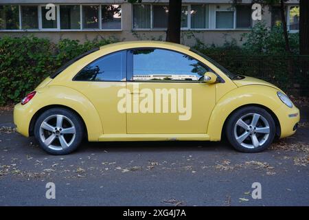 Bukarest, Rumänien - 6. Juli 2024: Seitenansicht des gelben Autos des Volkswagen Käfers, der vor einem Wohnblock geparkt ist Stockfoto