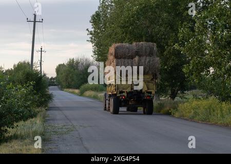 Traktor mit Heuballen im Anhänger auf Landstraßen im ländlichen Raum Stockfoto