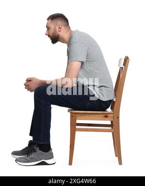 Mann mit schlechter Haltung, der auf einem Stuhl vor weißem Hintergrund sitzt Stockfoto