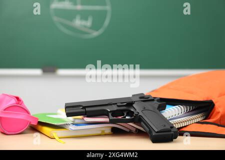 Schulpapier und Pistole auf dem Schreibtisch im Klassenzimmer, Nahaufnahme Stockfoto