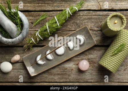 Flache Lagenkomposition mit Räucherstäbchen schwelend in Halter auf Holztisch Stockfoto