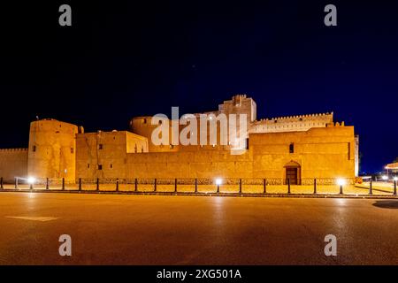 Jabreen Zitadelle Festung Steinmauern und runder Bastionturm in Nachtbeleuchtung, Bahla, Sultanat Oman Stockfoto