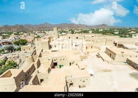 Bahla Zitadelle Festung Innenhof Gebäude und Rundturm mit Stadt im Hintergrund, Bahla, Oman Stockfoto