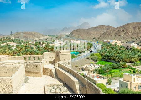 Bahla Zitadelle Festung Innenhof und runder Turm mit Stadt und Straße im Hintergrund, Bahla, Oman Stockfoto