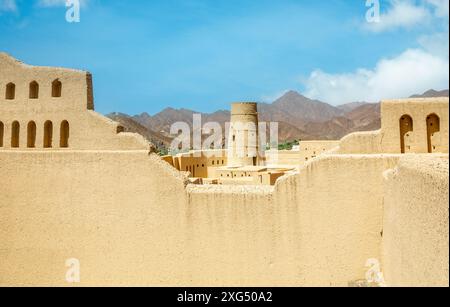 Bahla Zitadelle Festung Steinmauern und runde Türme mit Bergen im Hintergrund, Bahla, Sultanat Oman Stockfoto