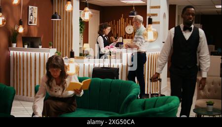 Das Hotelpersonal überprüft den Pass eines älteren Kunden, der in einem luxuriösen Ferienresort ankommt, im Ruhestandsalter. Eine Angestellte half der Person beim Einchecken und begrüßte den Mann in der Lobby. Stockfoto