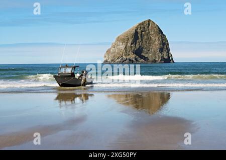 Ein Dory der Pacific City Dory Fleet wartet auf seinen Wohnwagen am Strand von Pacific City, Oregon. Heuhaufen Rock ist im Hintergras Stockfoto