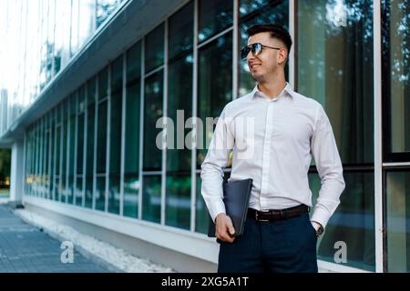 Ein Mann mit Hemd und Krawatte steht vor einem Gebäude. Er wirkt selbstbewusst und professionell. Stockfoto