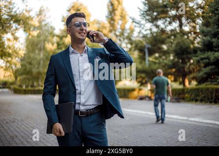 Ein Mann läuft die Straße der Stadt entlang, während er mit seinem Handy telefoniert. Stockfoto