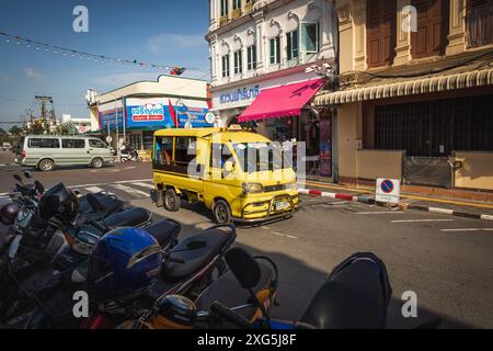 Thailand. Phuket Yellow Tuk Tuk lokaler Taxidienst in der Altstadt mit chinesisch-portugiesischen Gebäuden. Motorräder parkten auf der Straßenseite. Geschäfte und Stockfoto