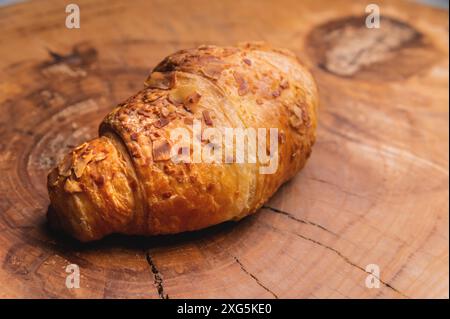 Nahaufnahme eines köstlichen Croissants mit Mandeln auf einer Holzpalette. Leckeres und gesundes Frühstück Stockfoto