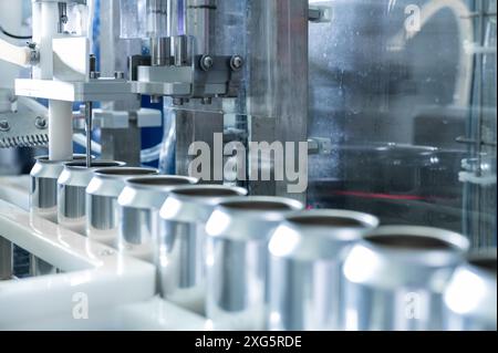 Leere neue Aluminiumdosen für die Getränkeverarbeitung in der Fabriklinie an der Förderbandmaschine in der Getränkeherstellung. Lebensmittel- und Getränkeindustrie Stockfoto