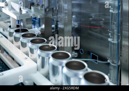 Leere neue Aluminiumdosen für die Getränkeverarbeitung in der Fabriklinie an der Förderbandmaschine in der Getränkeherstellung. Lebensmittel- und Getränkeindustrie Stockfoto