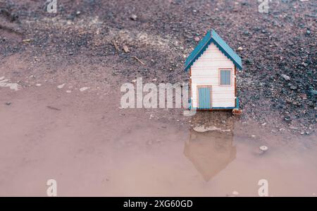 Kleines Haus auf einer Straße mit einer großen Pfütze, Immobilienkonzept, Miete oder Kauf eines Hauses, Reise- und Urlaubssymbol Stockfoto