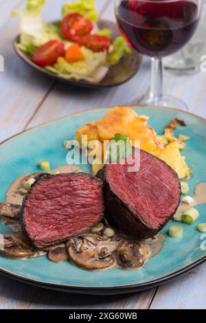 Geschnittenes Steak und Kartoffelgratin auf einem Teller Stockfoto