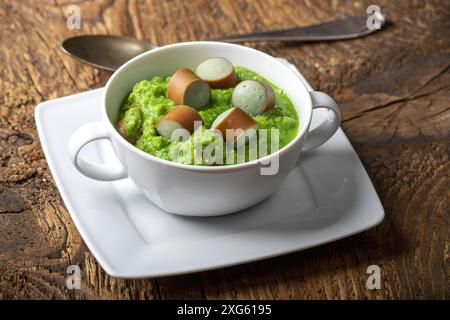 Cremige Erbsensuppe auf dunklem Holz Stockfoto