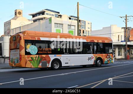 Seitenansicht eines neuen Volvo BZL Elektrobusses, der von der CDC Melbourne betrieben wird, mit PTV-Lackierung, der durch eine Einkaufsstraße in den Vororten fährt Stockfoto