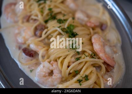 Weißwein, Sahne, Garnelen und Spaghetti mit Speck, serviert auf einem Teller Stockfoto