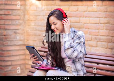 Glückliche junge lateinfrau, die im Internet surft, mit einem digitalen Tablet im Freien. Stockfoto
