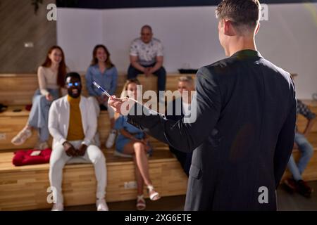 Rückansicht auf männlichem Lautsprecher, der im Konferenzsaal spricht und mit Stift an der Seite einer Geschäftsveranstaltung zeigt. Publikum im Konferenzsaal. Business und EN Stockfoto