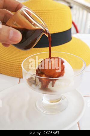 Mit der Hand einen Espresso auf Vanilleeis für eine Tasse Affogato gießen Stockfoto
