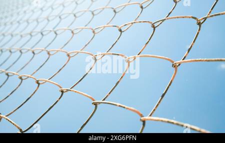 Metallzaun Drahtnetz auf blauem Himmel Hintergrund Stockfoto