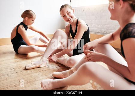 Ballett, Gruppe und Mädchen Tänzerin mit Schuhen in der Kreativschule, Kunstakademie und Tanzstudio mit Freunden auf dem Boden zum Üben. Glückliche Studenten, Künstler Stockfoto