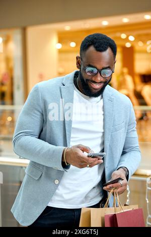 Man schaut das Bankkonto nach erfolgreichem Shopping in der Mall. Nahaufnahme des Fotos. Ein Typ, der seiner Freundin sms schickt, sms schickt. Ein Typ mit erstaunt schockiert Stockfoto