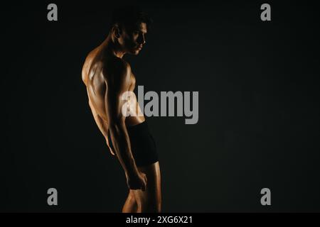 Muskulös geschnittener Mann, der bauch- und Armmuskeln in einem Studio zeigt Stockfoto