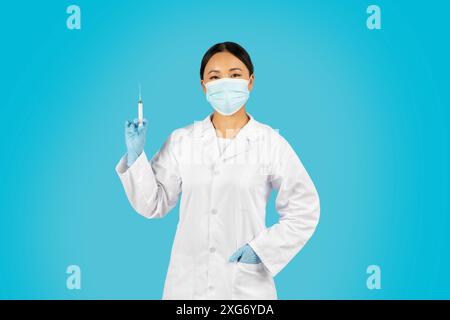 Frau Im Gesundheitswesen, Die Spritze Vor Blauem Hintergrund Hält Stockfoto
