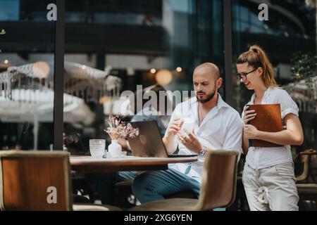 Geschäftsleute arbeiten an einem Projekt in einer modernen Kaffeebar zusammen, arbeiten gemeinsam und tauschen Ideen aus der Ferne aus Stockfoto