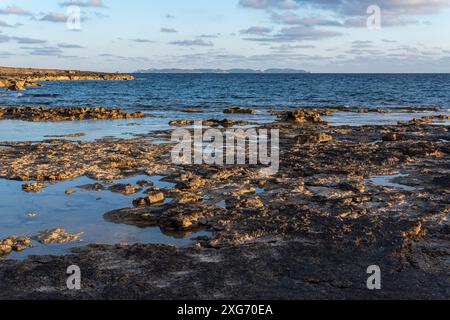 Landschaft der felsigen Küste der Insel Mallorca mit der Insel Cabrera im Hintergrund bei Sonnenuntergang. Spanien Stockfoto