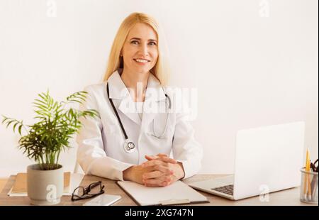 Ärztin sitzt am Schreibtisch mit Laptop Stockfoto