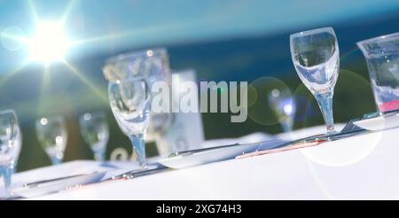 Gedeckter Tisch mit Gläsern und Geschirr bei Sonnenschein. Stockfoto