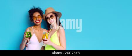 Zwei Frauen genießen Sommercocktails vor blauem Hintergrund Stockfoto