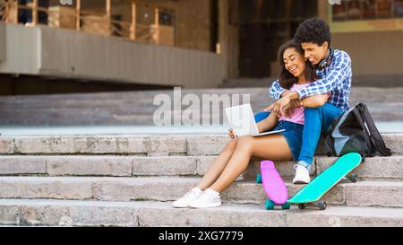Paare, die auf Steintreppen sitzen, mit Laptop und Skateboards Stockfoto