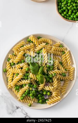 Vegetarische Pasta mit gekochten grünen Erbsen und Basilikum auf Teller Stockfoto