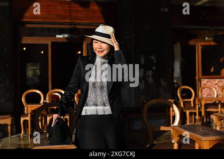 Carpe diem, ein glamouröser, gut gekleideter Tourist, steht zwischen hölzernen Cafés in der Sonne und genießt morgens den Blick auf Venedig am Dogenpalast Stockfoto