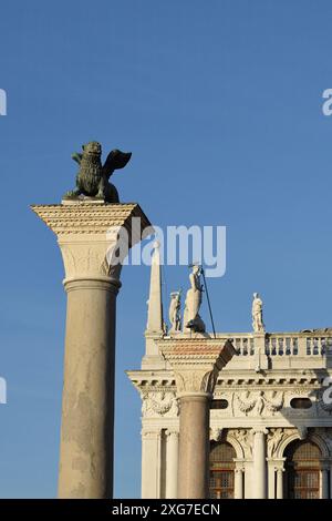 Mit Blick auf die Säulen des Löwen von St. Markus und St. Theodore und Statuen auf der Balustrade, Biblioteca Nazionale Marciana vor einem blauen Himmel Stockfoto