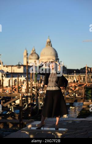 Genießen Sie die Aussicht auf Venedig an einem sonnigen Morgen, ein stilvoller, gut gekleideter Tourist am Ufer, vertäute Gondeln, Santa Maria della Salute blauer Himmel Stockfoto