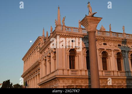 Mit Blick auf die Säulen des Löwen von St. Markus und St. Theodore und Statuen auf der Balustrade, Biblioteca Nazionale Marciana vor einem blauen Himmel Stockfoto