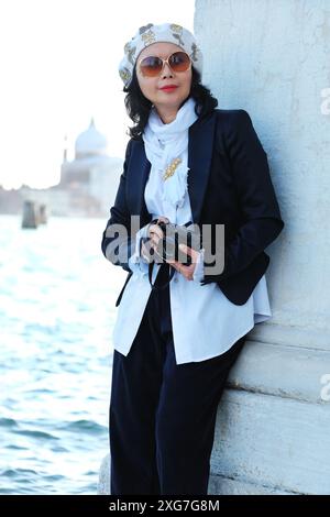 Eine glamouröse, gut gekleidete Frau, die eine Kamera in der Punta della Dogana hält, Blick über den Markusplatz nach San Giorgio Maggiore Stockfoto