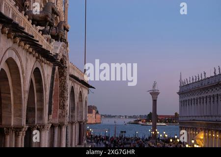 Blick auf die Piazzetta San Marco Säule Saint Theodore und klassische Statuen auf der Balustrade der Biblioteca Nazionale Marciana vor einem blauen Himmel Stockfoto