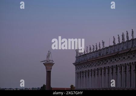 Blick auf die Piazzetta San Marco Säule Saint Theodore und klassische Statuen auf der Balustrade der Biblioteca Nazionale Marciana vor einem blauen Himmel Stockfoto