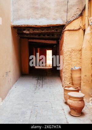 Eine enge Gasse mit Tontöpfen und strukturierten Wänden in einem rustikalen mediterranen Dorf, die ein Gefühl von Geschichte und Charme vermittelt. Stockfoto